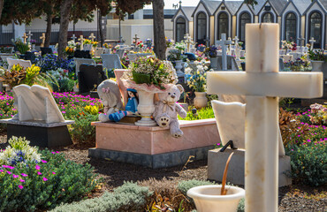 Trauer um ein Kind: Friedhof mit Kindergrab, Teddybären und Puppe