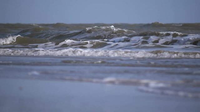 sea waves crashing at the beach at Mandvi at Kutch, Gujarat, India. Beautiful tropical beach with blue sky with waves crashing empty beach during summer