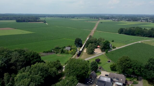 Dutch steam locomotive with wagons driving through Veluwe landscape