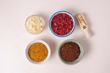 Colourful set different spices for meat, vegetarian dishes in bowls on light background. Seasoning pink peppercorns, dried onions, sun dried tomatoes, curry. Hot spicy for cooking