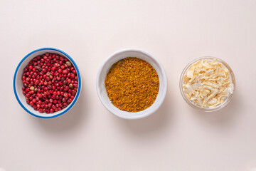Colourful set different spices for meat and vegetarian dishes on beige light background. Seasoning pink peppercorns, dried onions, curry. Hot spicy background for cooking. Interesting taste for soup