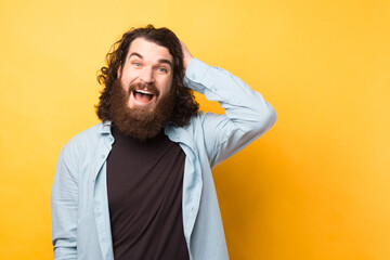 Photo of bearded curly man with shocked, amazed expression isolated on yellow background