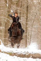 a beautiful woman rides through the snowy countryside and points her bow straight ahead