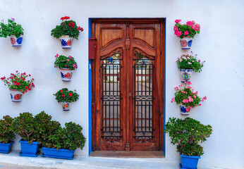 Fototapeta na wymiar Beautiful facade of a house in Chelva Valencia (Spain) adorned with flowerpots with flowers, and a rustic wooden door.