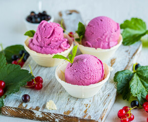 Homemade ice cream with black currants in a waffle cup on a light concrete background. Ice cream recipes.