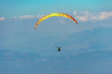 Paraglider soaring on paragliding in the sky in mountain. Extreme sport in mountains
