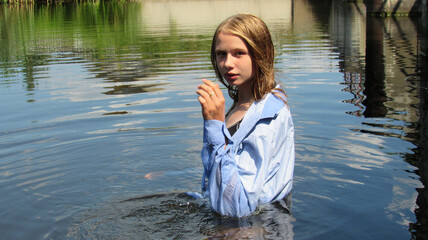 A young and beautiful girl in a shirt posing in the water