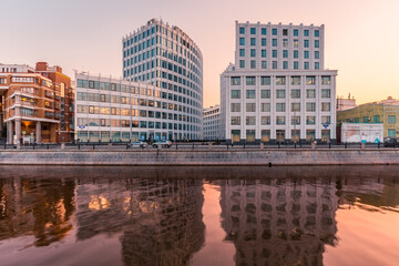 Sunset cityscape featuring modern office buildings on a river bank