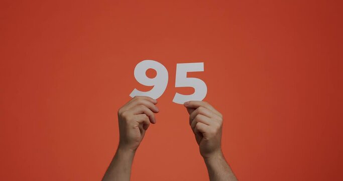 Number ninety-five in hands. Man showing digits, 95 made of carved paper for voting, mathematics learning or sale