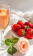 Strawberries with a glass of rose wine . Vintage roses Pierre de Ronsard, eden rose on a white background