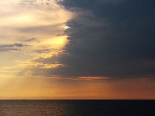 Naklejka na ściany i meble A thundercloud covers the sun. Beautiful sunset over the sea.