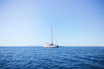 Obraz premium One white lonely yacht in the middle of the sea