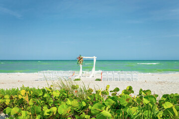 View of ceremony location on beach with no people, blue sky and shoreline in background