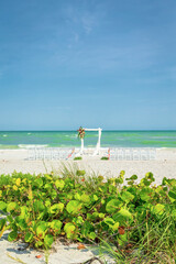 View of ceremony location on beach with no people, blue sky and shoreline in background