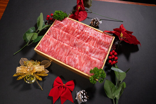 Closeup of raw wagyu cut steak slices on a wooden board on the table with Christmas ornaments on it