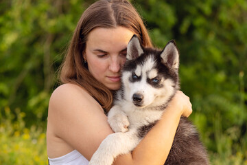 Naklejka na ściany i meble A beautiful young woman with her pet husky dog outdoors in the park