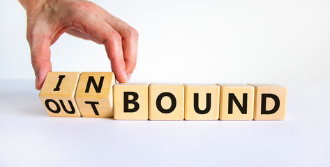 Inbound or outbound symbol. Businessman turns wooden cubes and changes the word 'outbound' to 'inbound'. Beautiful white table, white background. Business, inbound or outbound concept. Copy space.