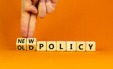 New or old policy symbol. Businessman turns wooden cubes and changes words 'old policy' to 'new policy'. Beautiful orange table, orange background. Business, old or new policy concept. Copy space.