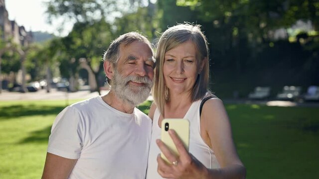 Elderly Man And Woman In The Park After Fitness Take Pictures Of Themselves On The Phone.