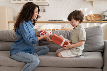 Surprised preschool child and mum unpacking presents. Young family of two people exchange gifts...