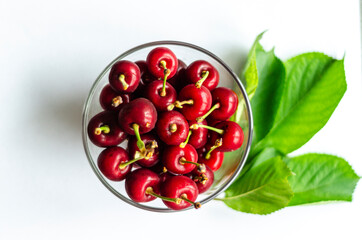 ripe cherry in a glass on a light background, free space