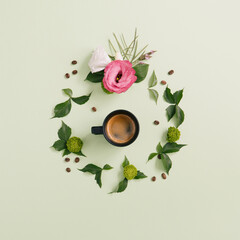 Espresso coffee cup with coffee beans and beautiful flowers with foliage on a pastel green background
