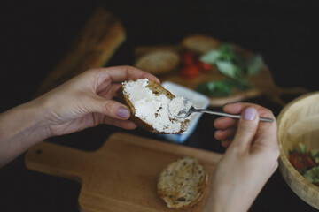 Close up of woman spreads curd cheese on a slice of bread
