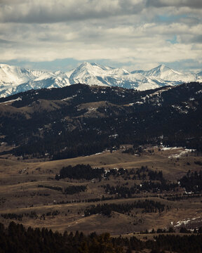 Snow covered mountains overlooking a brown valley on a cloudy day