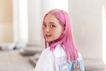 Portrait of a positive pink-haired teenage girl in a white T-shirt.Street style.Summer...