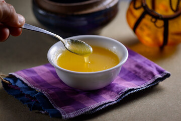 Ghee butter from India in white dinnerware container on wooden table.