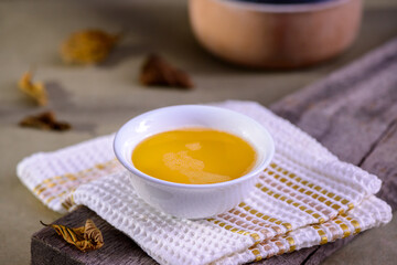 Ghee butter from India in white dinnerware container on wooden table.
