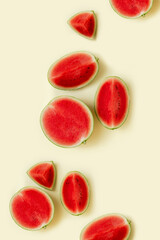Small watermelon on a sunny yellow pastel background. Trendy summer fruits and refreshments. Minimal summer food concept.