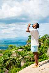 african tourist drinks water after climbing a rock