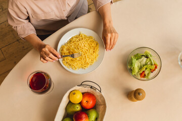 Mature senior woman in the kitchen preparing or eating tasty, homemade pasta in kitchen. Top view.