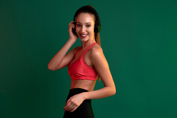 Young smiling sportive girl listening to music on headphones after playing sports exercise