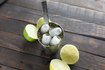 Copo, erva e bomba de tereré( terere)  em uma mesa de madeira com iimões 