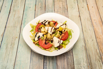 gourmet salad with chopped apple, fresh cheese, tomato, peanuts, sliced tomato and iceberg lettuce