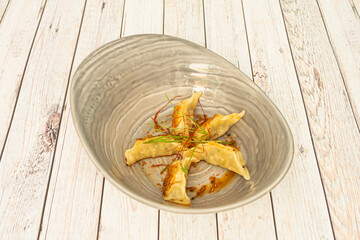Grilled fried chicken stuffed gyozas with saffron filaments on a gray bowl