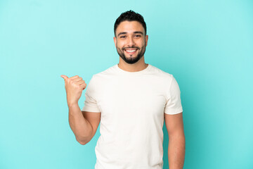 Young arab man isolated on blue background pointing to the side to present a product