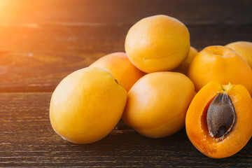 Several natural apricots from the home garden. Apricots on a plank table. One apricot is cut in half.