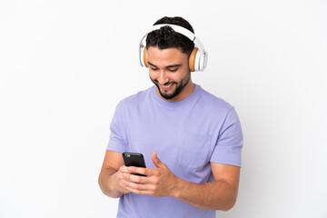 Fototapeta premium Young arab man isolated on white background listening music and looking to mobile