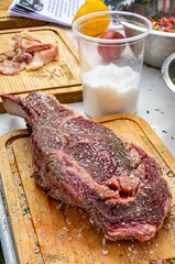 cowboy  crudo y sal pimentado listo para asar.

corte de res condimentado sobre tabla de madera listo para asar.

manos salpimentado corte crudo listo para asar 