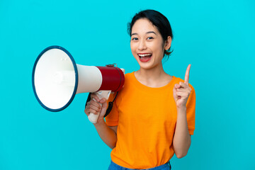 Young Vietnamese woman isolated on blue background holding a megaphone and pointing up a great idea