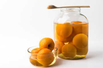 Peaches canned in a glass bowl and in a jar on a white background