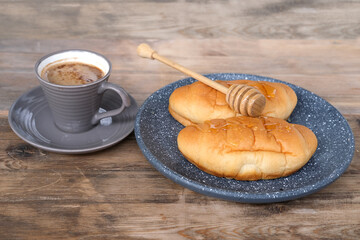 ruddy fresh croissants on a dark gray plate, sweet honey is pouring in a thin amber stream, fresh baked goods concept, breakfast, gain weight, lots of calories, unhealthy food