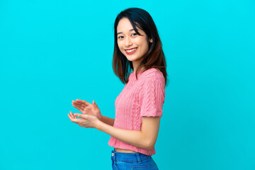 Young Vietnamese woman isolated on blue background applauding