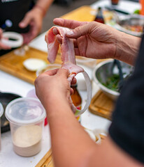 manos preparando aros de cebolla  cubriéndolos con tocino, Bacon , panceta 