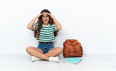 Young student woman sitting one the floor isolated on white background with surprise expression