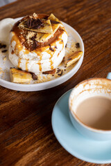 delicious sweet breakfast, pancakes with banana and strawberries, cream and chocolate, a cup of coffee