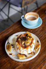 delicious sweet breakfast, pancakes with banana and strawberries, cream and chocolate, a cup of coffee